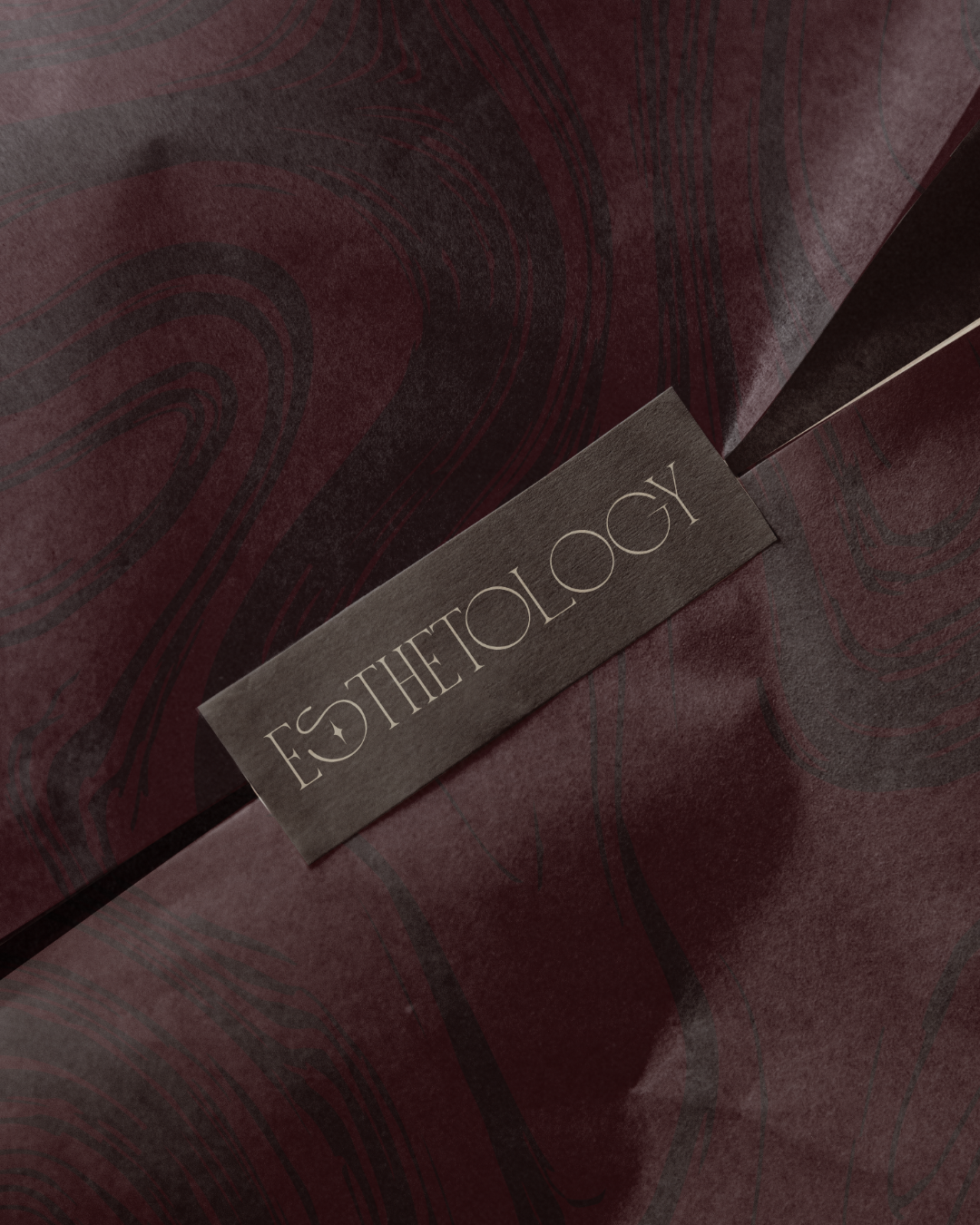 Maroon product packaging paper with 'Esthetology' branding on top
